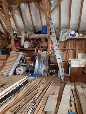 Dachboden mit Holzlatten, Leiter und Baumaterialien für Renovierung und Lagerung.