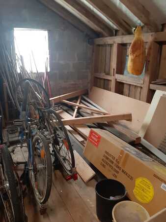 Dachboden mit alten Fahrrädern, Holzbrettern, Karton, Eimer und hängendem Schinken.