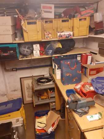 Ein Kellerraum mit Regalen, Werkzeug, Kartons und gelben Kisten zur Aufbewahrung.